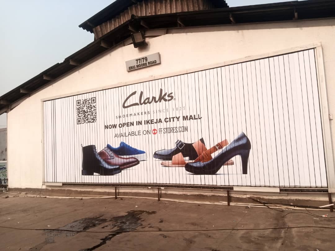 Clarks — "Now open in Ikeja City Mall" wall billboard.